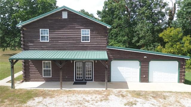 log home featuring covered porch and a garage