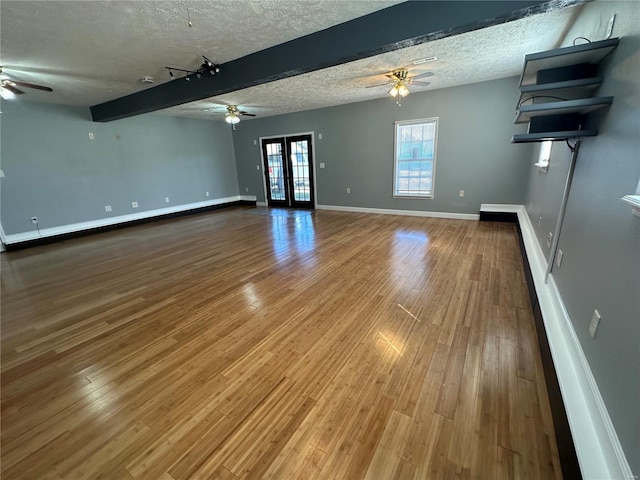 spare room featuring beam ceiling, ceiling fan, hardwood / wood-style floors, and a textured ceiling