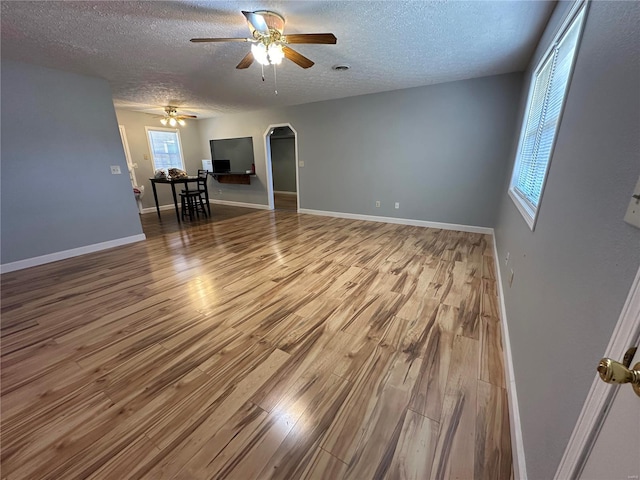 empty room featuring ceiling fan, plenty of natural light, and wood-type flooring