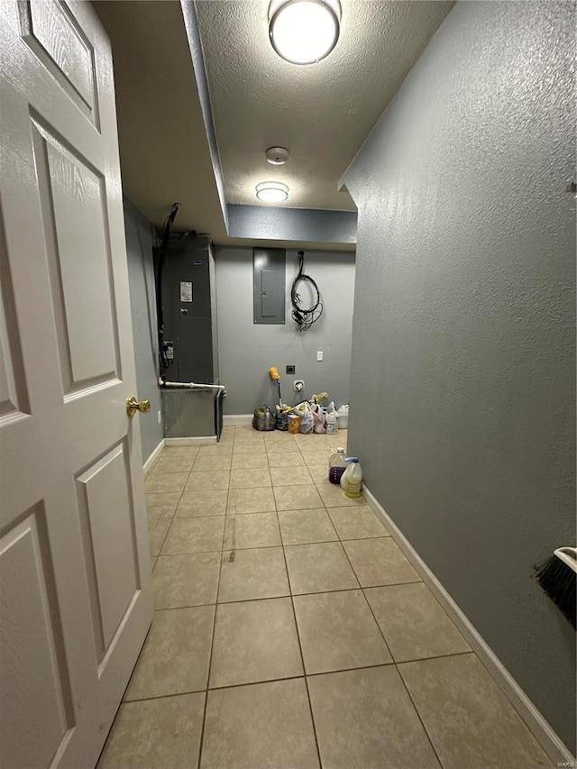 corridor with electric panel, light tile patterned floors, and a textured ceiling