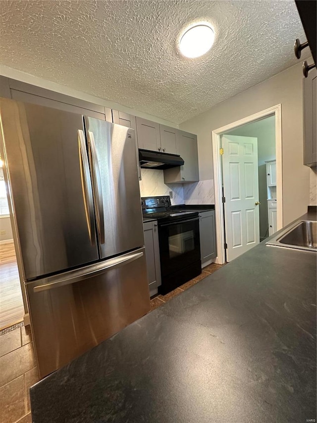 kitchen featuring gray cabinets, a textured ceiling, electric range, and stainless steel fridge