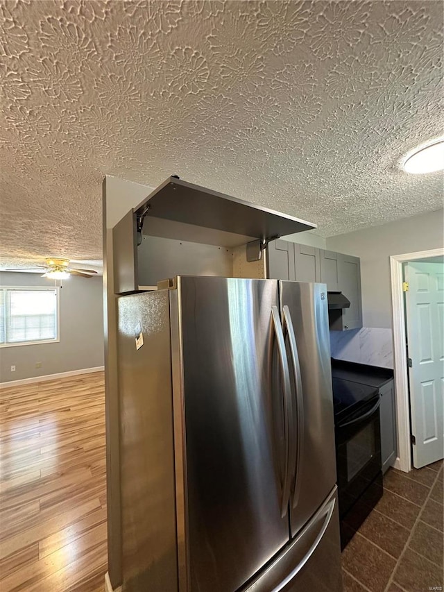 kitchen featuring stainless steel fridge, gray cabinetry, black electric range, a textured ceiling, and hardwood / wood-style floors