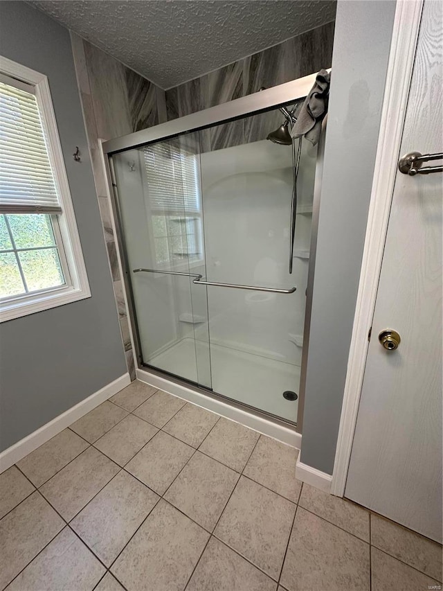 bathroom featuring a textured ceiling, tile patterned flooring, and a shower with door