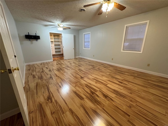 empty room featuring light wood-type flooring, a textured ceiling, and ceiling fan