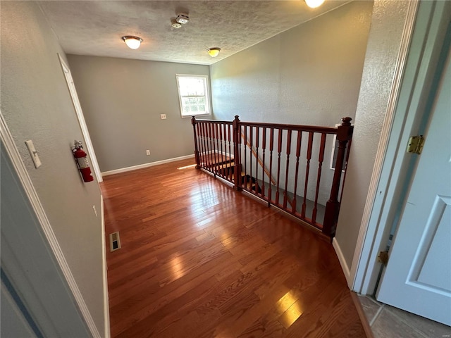 corridor featuring a textured ceiling and hardwood / wood-style floors