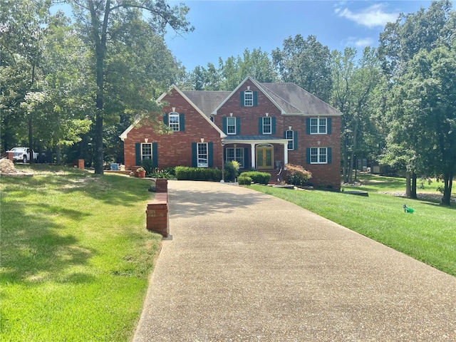 colonial home with a front lawn, brick siding, and driveway