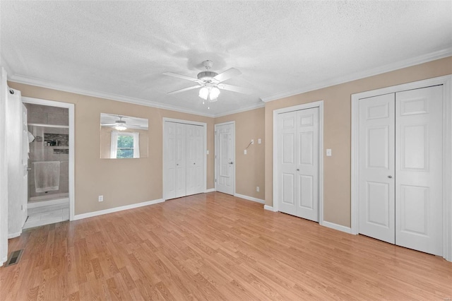 unfurnished bedroom featuring light hardwood / wood-style floors, a textured ceiling, ceiling fan, ornamental molding, and two closets