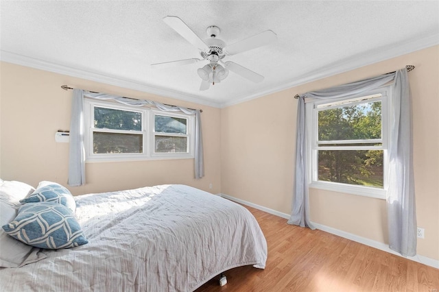 bedroom with ornamental molding, light wood-type flooring, ceiling fan, and a textured ceiling