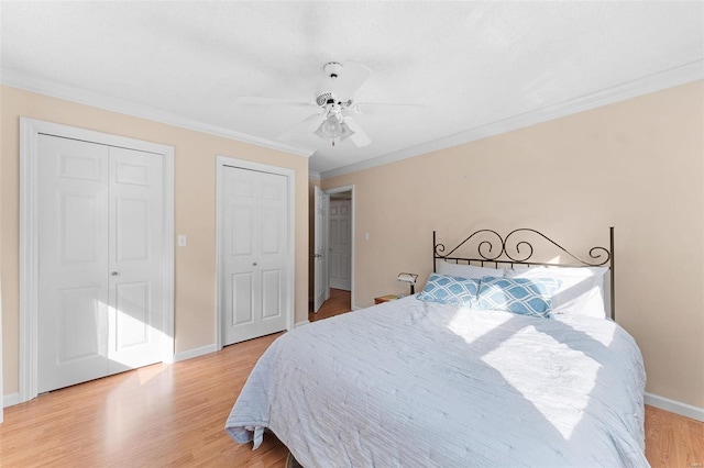 bedroom with crown molding, ceiling fan, multiple closets, and light hardwood / wood-style flooring