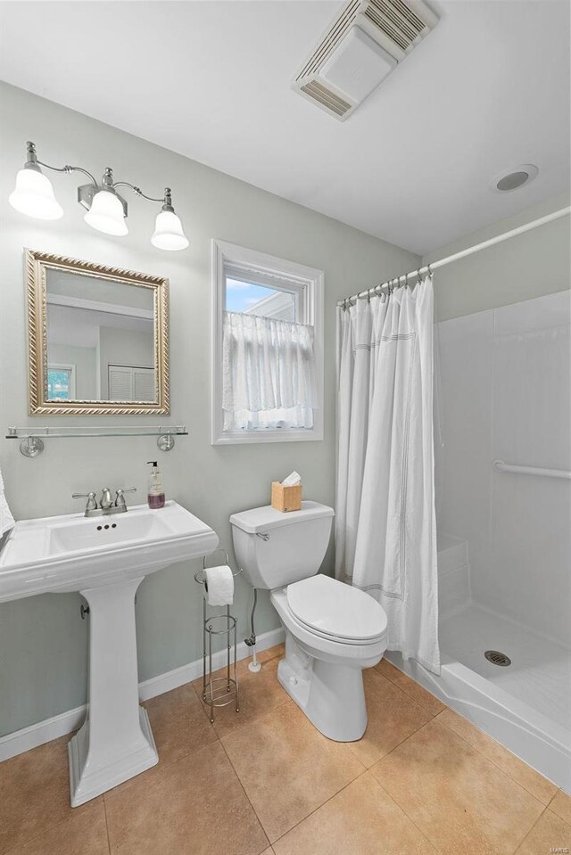 bathroom with curtained shower, toilet, and tile patterned floors