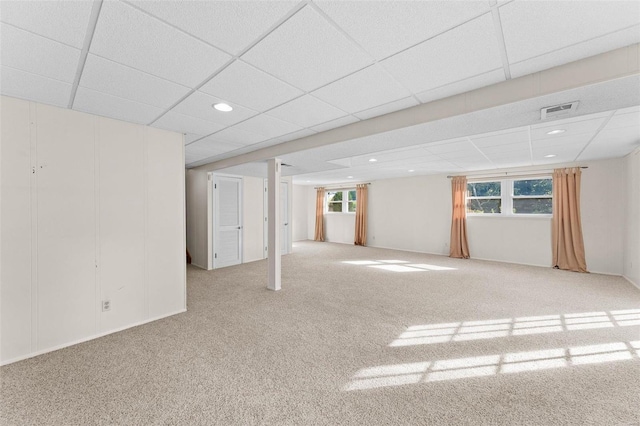 basement featuring light carpet and a paneled ceiling