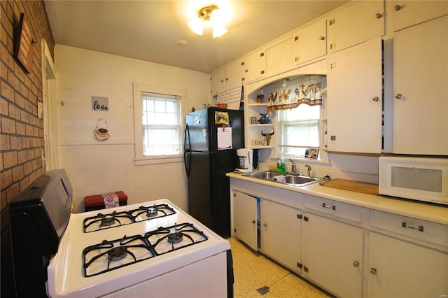 kitchen with white appliances, brick wall, sink, and white cabinets