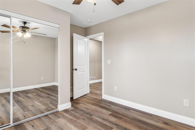 unfurnished bedroom with dark hardwood / wood-style floors, ceiling fan, and a closet