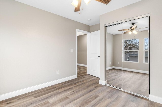 unfurnished bedroom with wood-type flooring, ceiling fan, and a closet