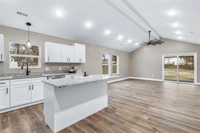 kitchen with white cabinetry, sink, light stone counters, and pendant lighting