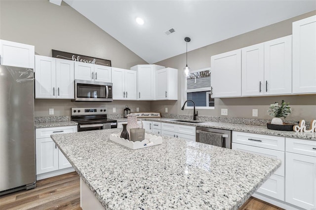 kitchen featuring pendant lighting, stainless steel appliances, sink, and white cabinets