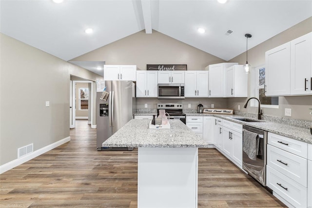 kitchen featuring stainless steel appliances, white cabinetry, a kitchen island, and light stone countertops