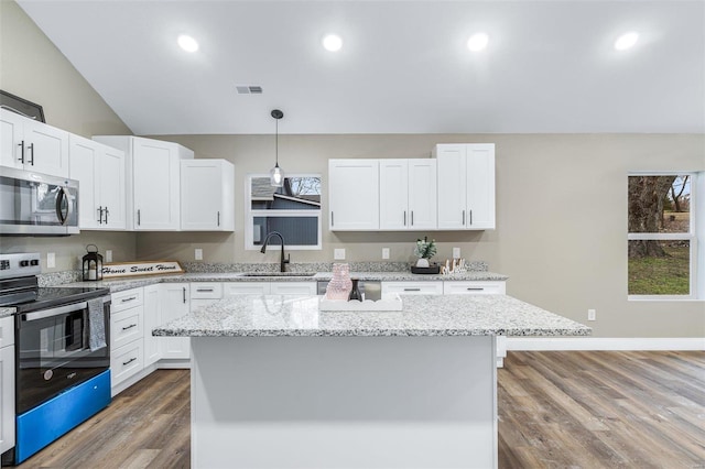 kitchen featuring electric stove, sink, a center island, white cabinets, and decorative light fixtures