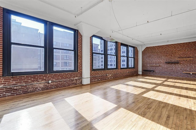 empty room with brick wall and wood-type flooring