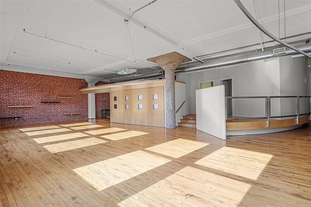 basement featuring light hardwood / wood-style flooring and brick wall