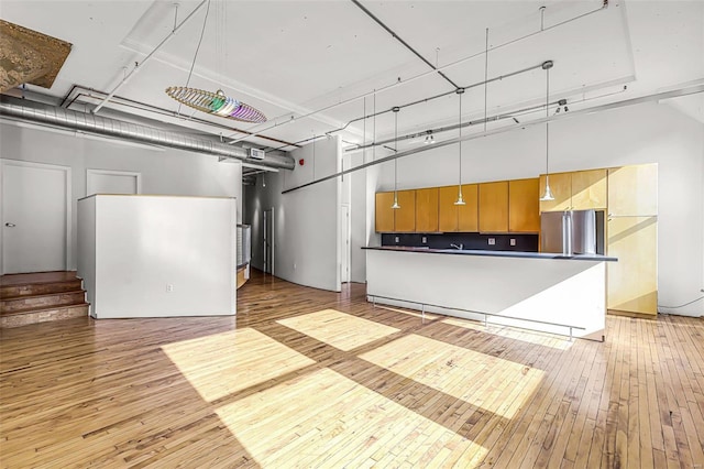 interior space featuring stainless steel fridge, light hardwood / wood-style flooring, and hanging light fixtures