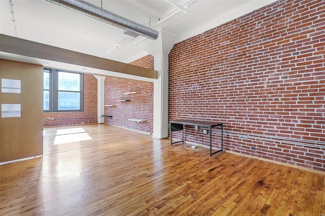 interior space with brick wall, a high ceiling, and light hardwood / wood-style floors