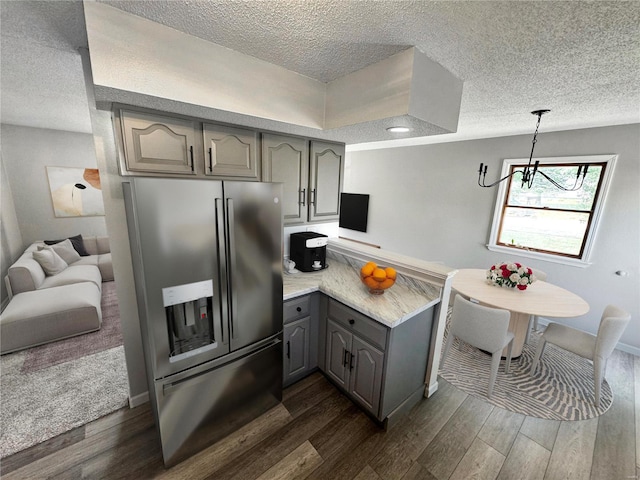 kitchen with gray cabinetry, dark hardwood / wood-style floors, stainless steel refrigerator with ice dispenser, and hanging light fixtures