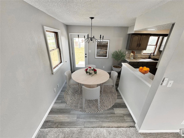 dining space with hardwood / wood-style floors, a textured ceiling, an inviting chandelier, and sink