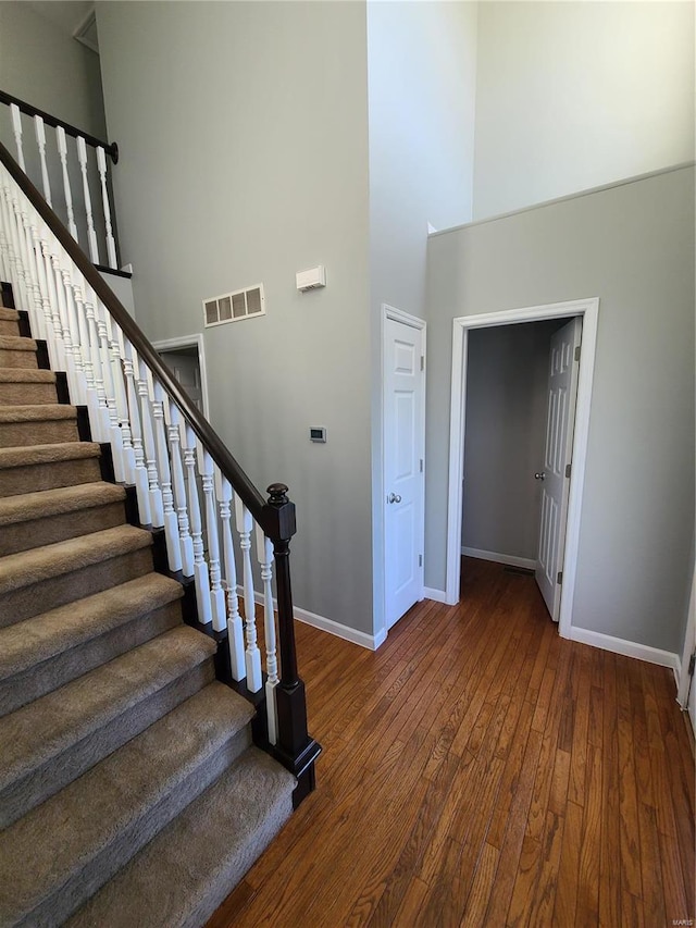 staircase featuring a high ceiling and wood-type flooring