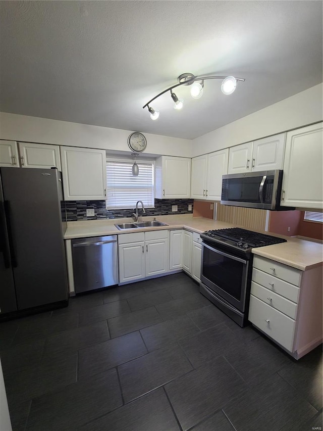 kitchen with decorative backsplash, sink, white cabinetry, and stainless steel appliances