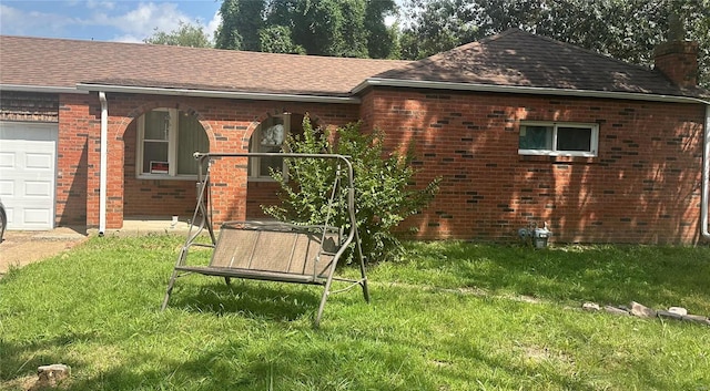 rear view of house with a garage and a lawn