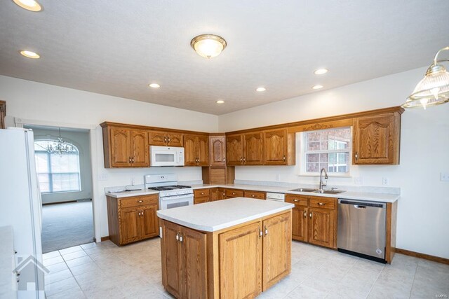 kitchen featuring plenty of natural light, sink, a center island, and white appliances