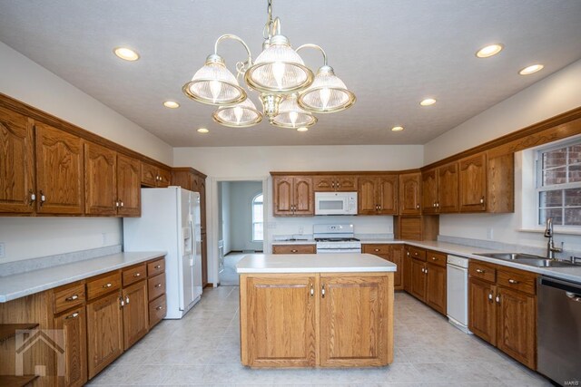 kitchen with white appliances, a chandelier, sink, pendant lighting, and a kitchen island