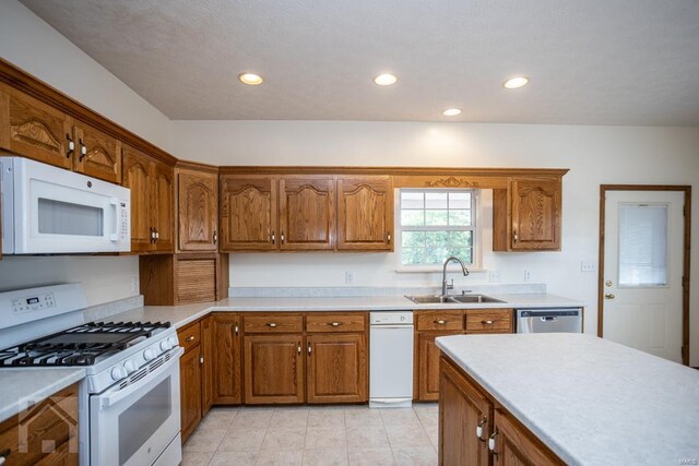 kitchen featuring light tile patterned floors, white appliances, and sink