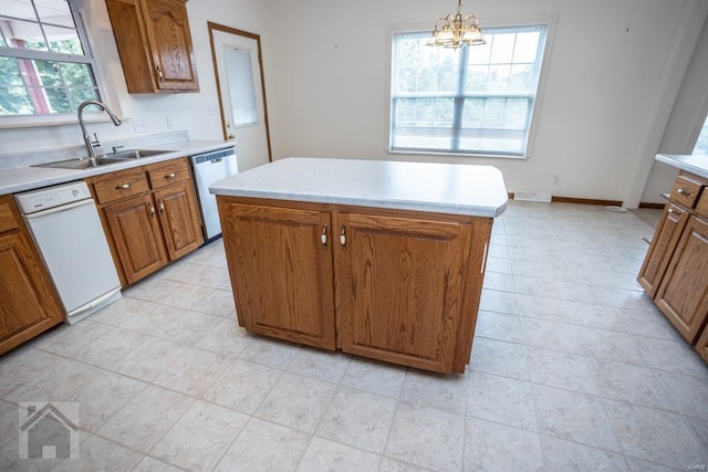 kitchen with a kitchen island, pendant lighting, stainless steel dishwasher, sink, and a chandelier