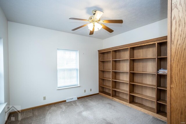 unfurnished room featuring ceiling fan, carpet, and a textured ceiling