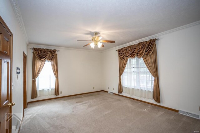 empty room with crown molding, light colored carpet, ceiling fan, and a textured ceiling