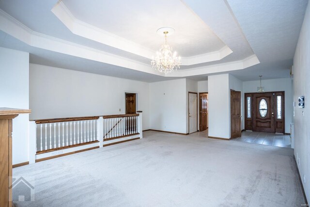 carpeted empty room featuring a raised ceiling, ornamental molding, and a chandelier