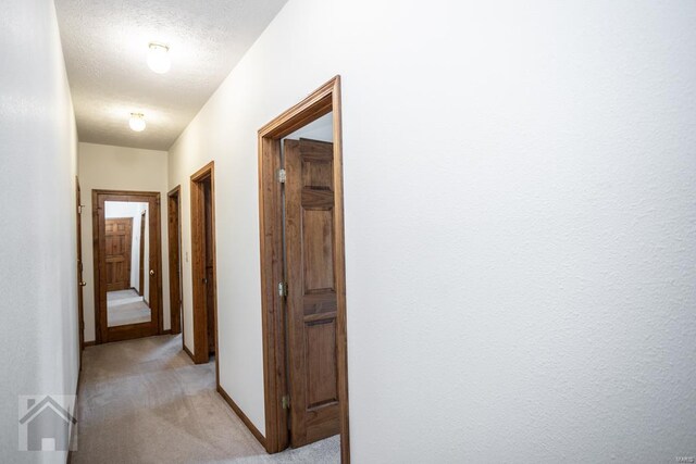 hall featuring a textured ceiling and light carpet