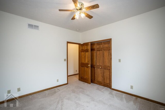 unfurnished bedroom with light colored carpet, ceiling fan, and a closet