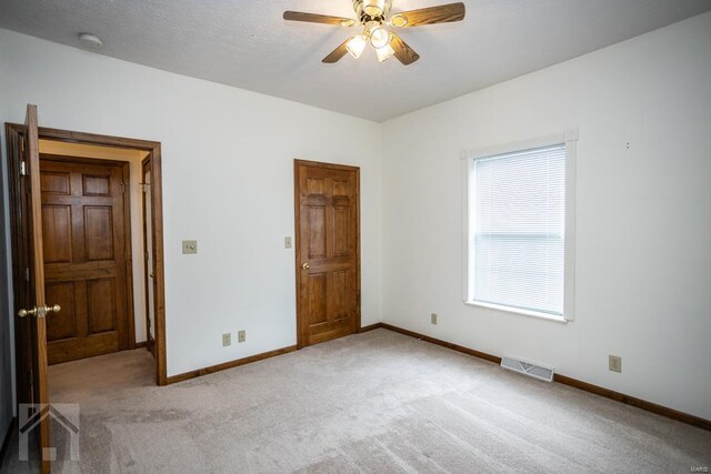 unfurnished bedroom featuring a textured ceiling, light colored carpet, and ceiling fan