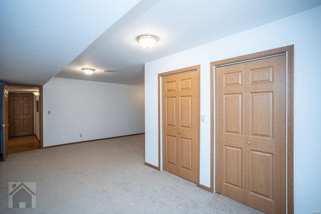 unfurnished bedroom featuring light carpet and two closets