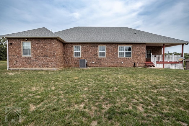 rear view of property with a lawn, a wooden deck, and central AC unit