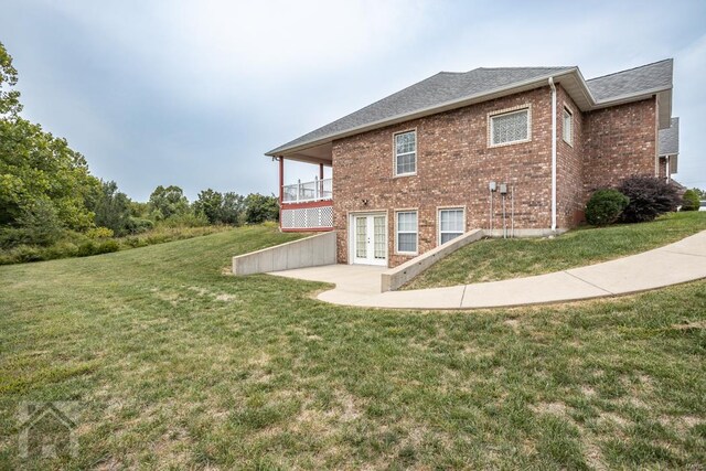 rear view of house with a balcony, a patio area, and a yard