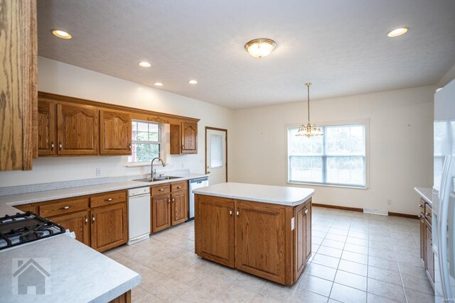 kitchen featuring an inviting chandelier, a center island, stainless steel dishwasher, sink, and hanging light fixtures