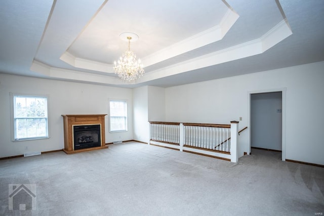 unfurnished living room featuring plenty of natural light, an inviting chandelier, a raised ceiling, and light carpet