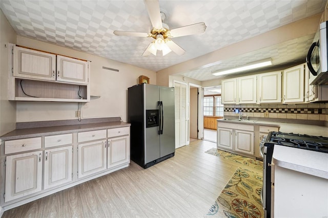 kitchen with tasteful backsplash, stainless steel appliances, ceiling fan, sink, and light hardwood / wood-style flooring