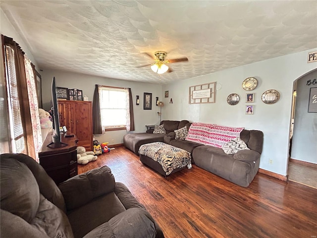 living room with dark hardwood / wood-style flooring, ceiling fan, and a textured ceiling