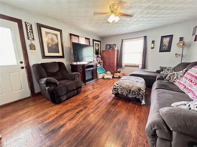 living room with a textured ceiling, ceiling fan, and dark hardwood / wood-style floors