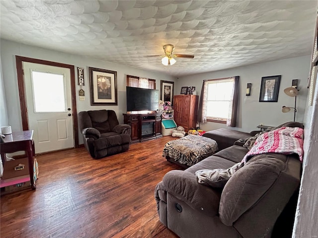 living room with a textured ceiling, ceiling fan, and dark hardwood / wood-style floors